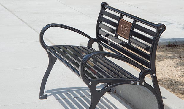 Schenley bench with a plaque on the sidewalk
