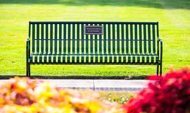 A Pullman Bench with Back and plaque in a garden setting