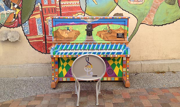 An Olivia Chair and piano in front of a wall mural