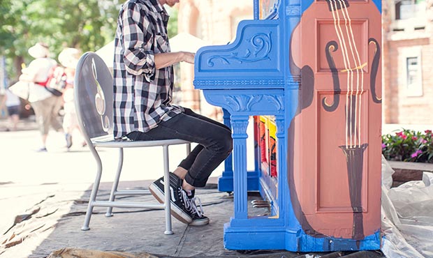 A pianist stops to play while sitting on an Olivia laser cut chair