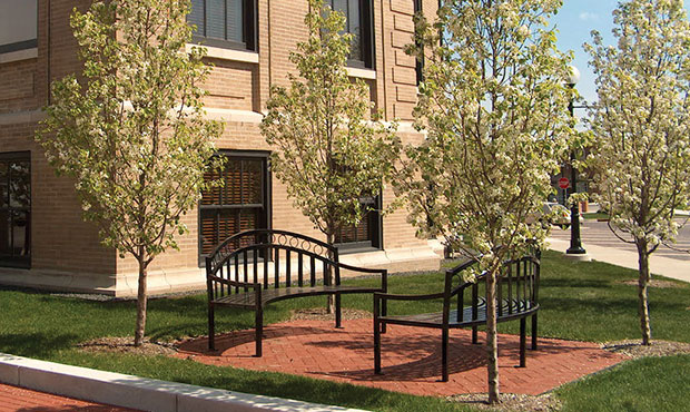 A pair of curved Atlanta Benches amidst blooming trees