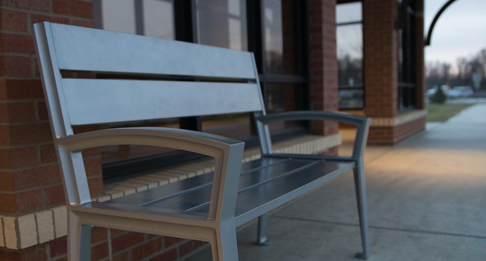 Everett Bench with Back situated at a public bus shelter